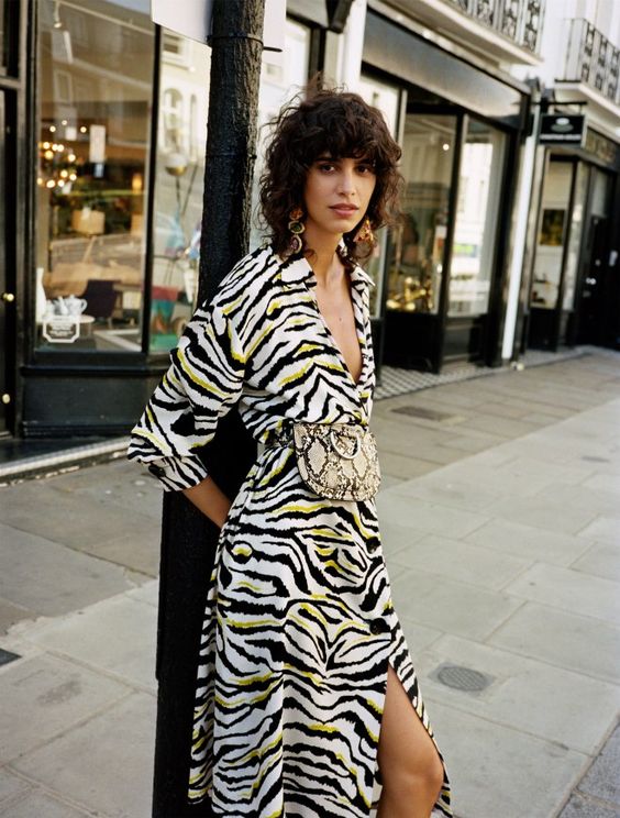 A model stands in a zebra print dress on the street.