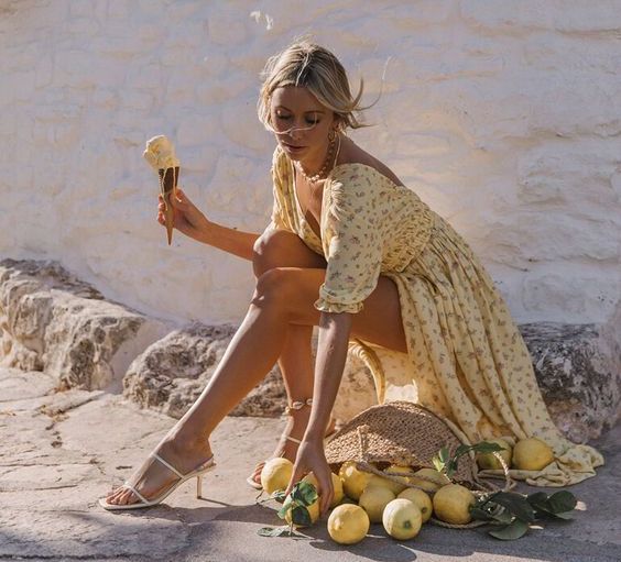 Girl in floral maxi dress picks up lemons from basket